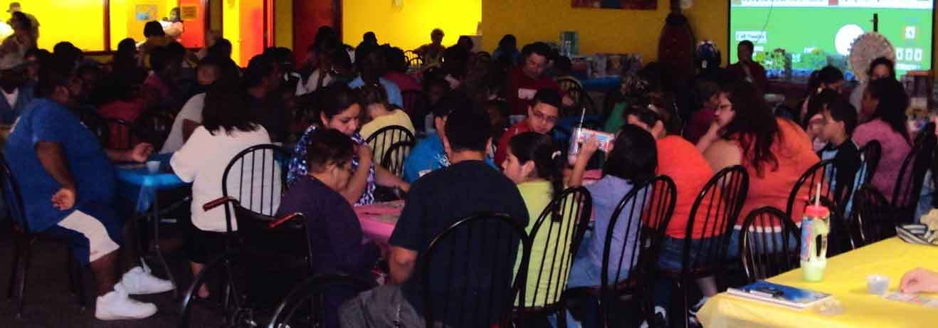 People gathered at tables surrounding projector screen